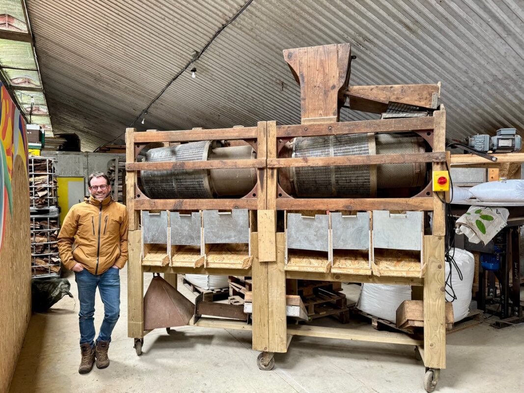 Un paysan céréalier à côté de son trieur alvéolaire, machine servant à trier les grains.