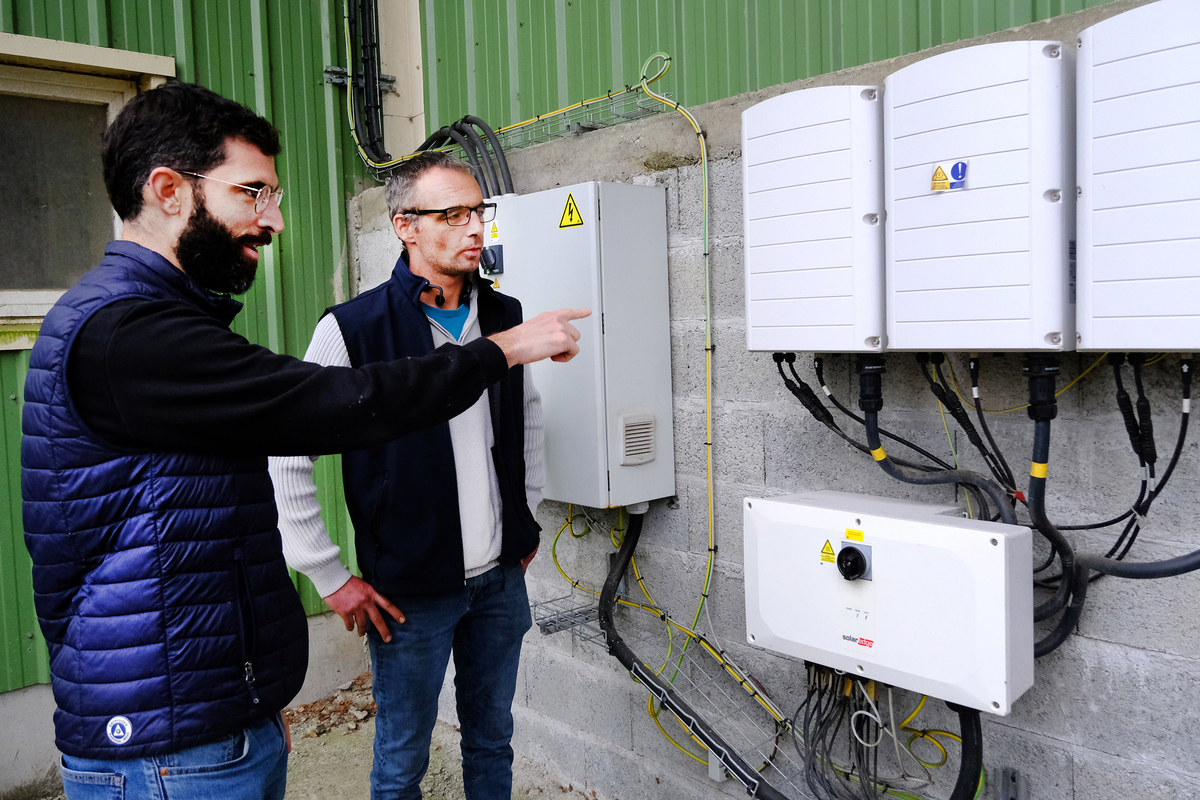 2 hommes devant un onduleur - Illustration Photovoltaïque : une étude complète pour faire le bon choix