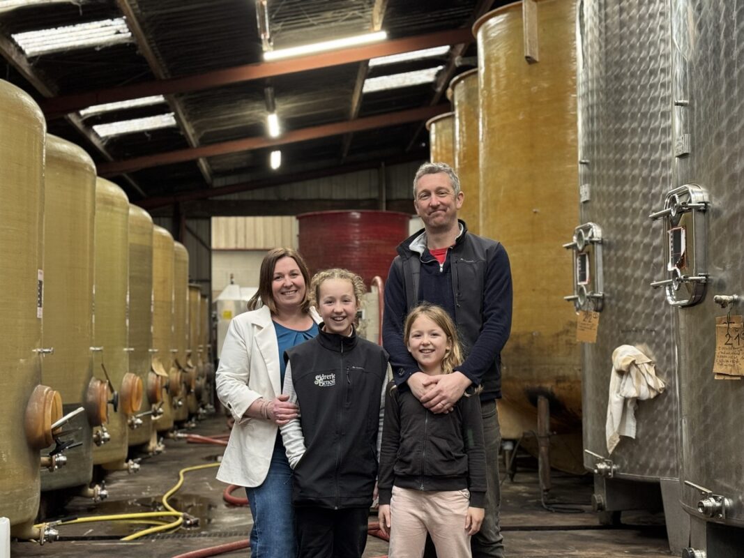 Des parents avec leur deux filles au milieu des cuves d'une cidrerie